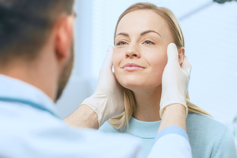 Doctor examining a female patient's face